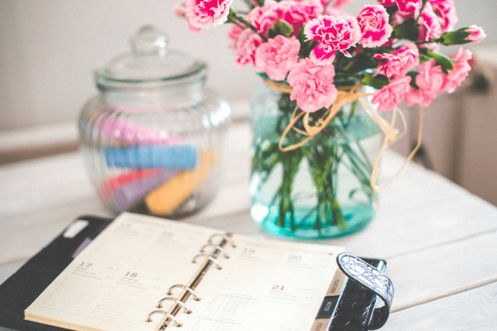 A table with a planner and flowers on top