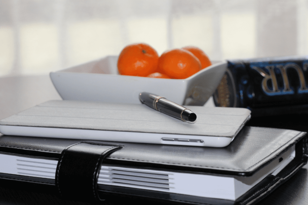 Tangerines on a plate and a laptop and paper on a table